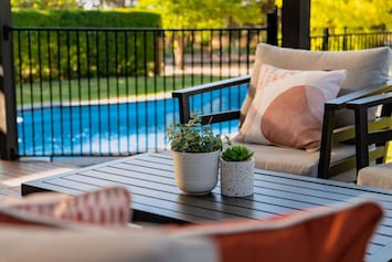The outdoor table sits gracefully in the open air, adorned with small plants that bring a touch of natural charm. Their vibrant greenery enhances the space, adding warmth and life to the setting. Whether for casual gatherings or peaceful moments, the scen