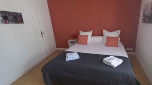 A bedroom with a bed, pillows, a nightstand, and a window. - Joli Appartement Avec 2 Chambres (Périgueux)