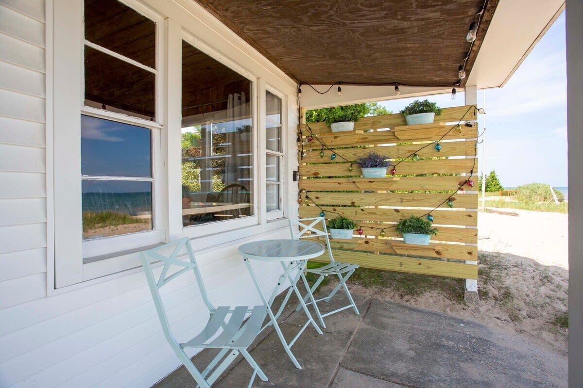 Un patio cubierto con un muro de listones de madera, mobiliario exterior y plantas en macetas.
