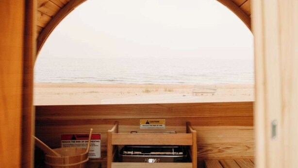 A wooden sauna with a view of the beach.
