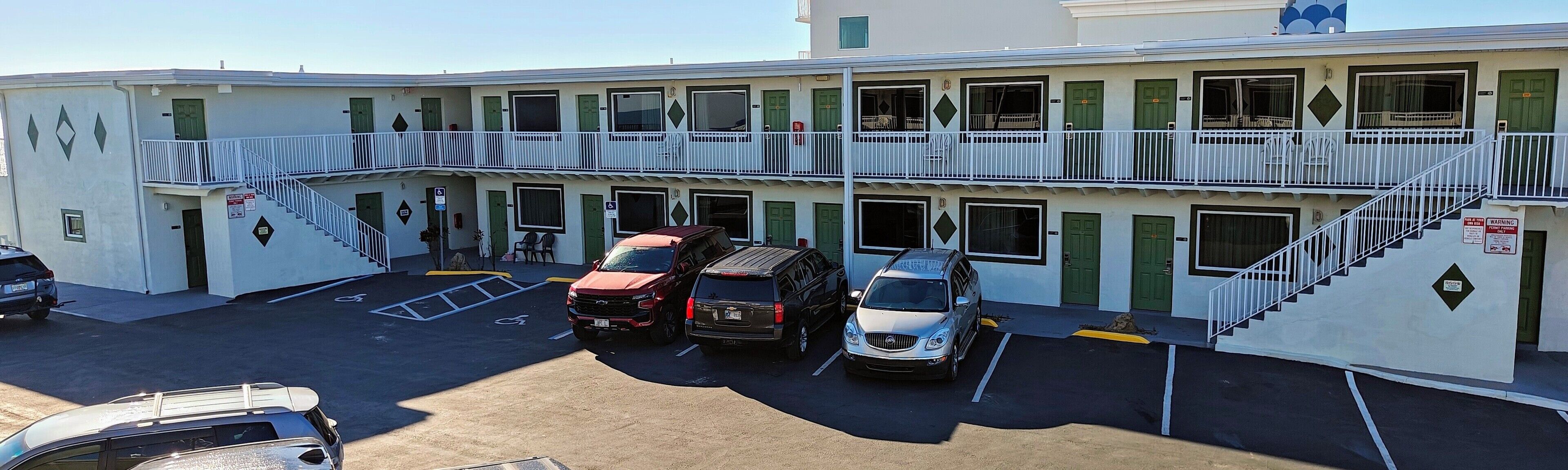 A multi-story building with a parking lot, featuring a staircase and a balcony.