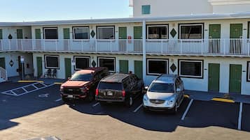 A multi-story building with a parking lot, featuring a staircase and a balcony.