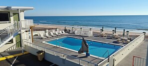 Ein Poolbereich mit Liegestühlen und Blick auf den Strand.