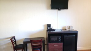 A small kitchenette with a microwave, coffee maker, and a TV mounted on the wall. - Oceanfront Inn and Suites (Ormond Beach)