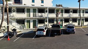 A multi-story hotel with balconies, a parking lot, and a view of the ocean. - Oceanfront Inn and Suites (Ormond Beach)