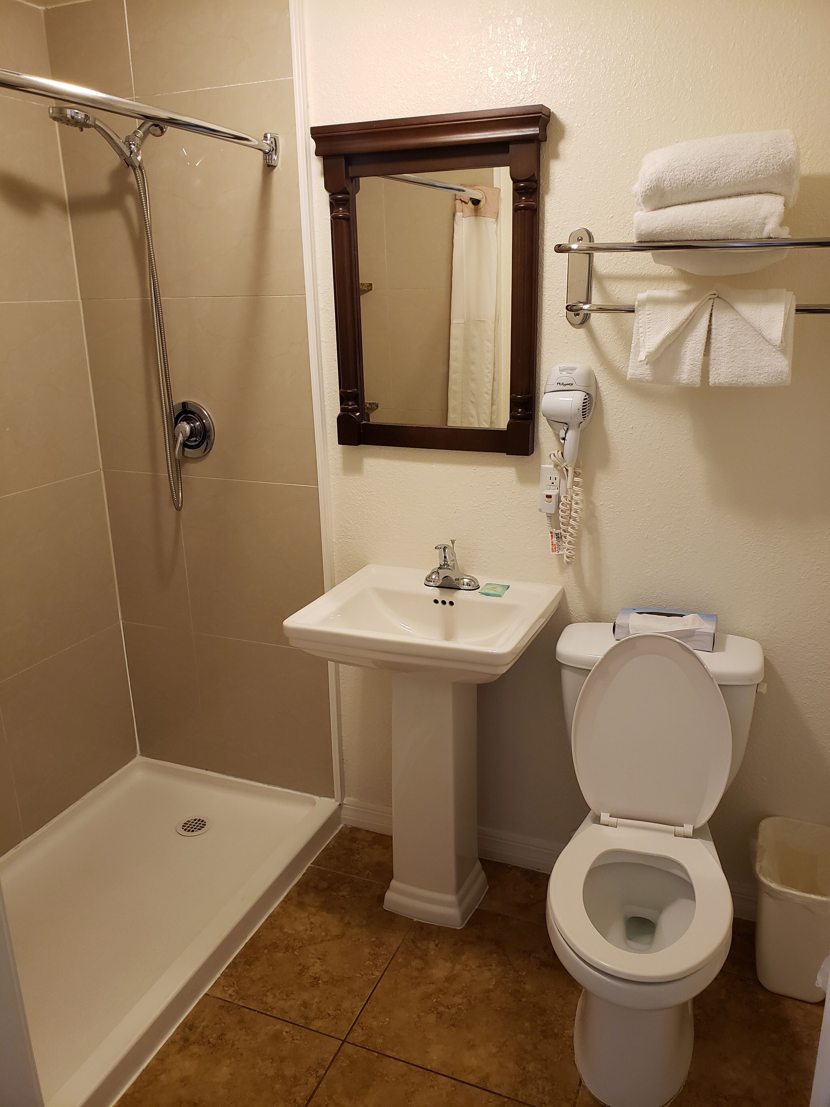 A bathroom with a shower, sink, toilet, and a towel rack.