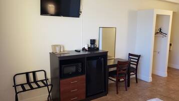 Una habitación compacta con kitchenette, televisor montado en la pared, una mesa de comedor con sillas y un vestidor.