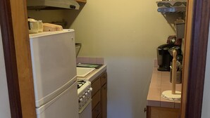 A compact kitchen with wooden cabinets, a white refrigerator, a stove, and a sink. - Walk to Beach, shops, restaurants and much more! (Long Beach)