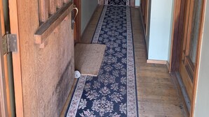 A hallway with a wooden door, a patterned carpet, and a staircase with a green mat. - Walk to Beach, shops, restaurants and much more! (Long Beach)