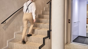 A person descending a carpeted staircase with a handrail, leading to a door with a metal handle. - Joe's Gomila Boutique Hotel (Palma de Mallorca)