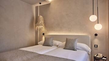 A modern bedroom with a large bed, a hanging light fixture, and a bedside table with a telephone.