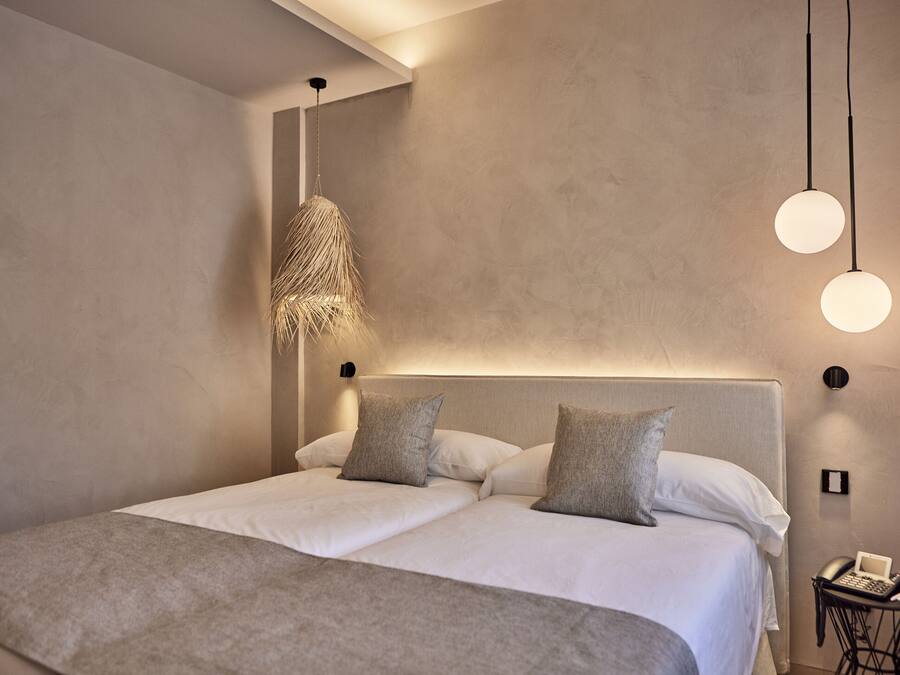 A modern bedroom with a large bed, a hanging light fixture, and a bedside table with a telephone.