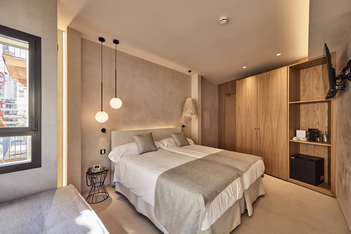 Une chambre d’hôtel moderne dotée d’un grand lit, d’une armoire, d’un bureau et offrant une vue sur la ville.