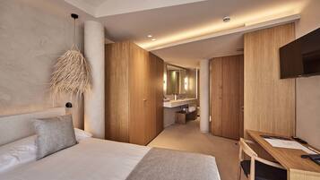 A modern hotel room with a large bed, a desk, and a TV.