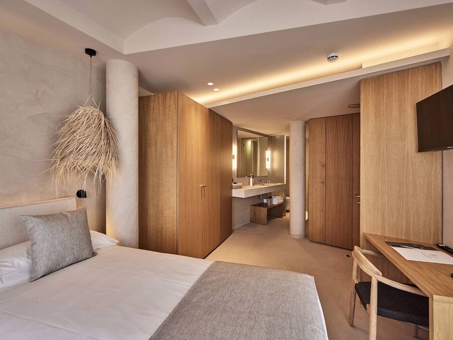 A modern hotel room with a large bed, a desk, and a TV.