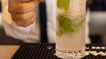 A person holding a glass with a lemon slice and mint leaves.