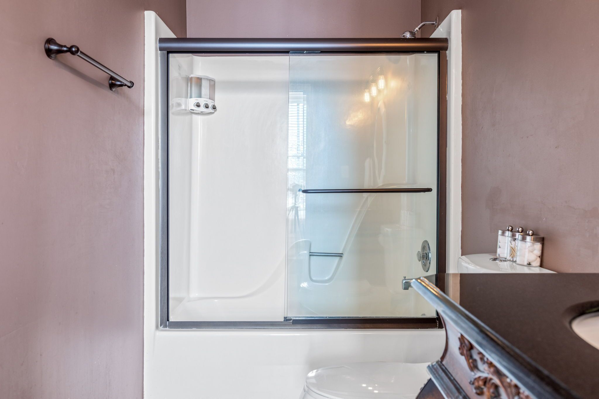 A modern bathroom with a glass-enclosed shower, a white toilet, and a marble countertop.