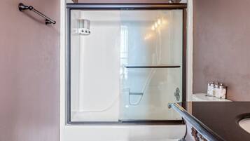 A modern bathroom with a glass-enclosed shower, a white toilet, and a marble countertop.