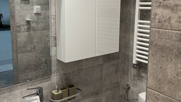 A modern bathroom with a white cabinet, a sink, a mirror, and a towel rack.