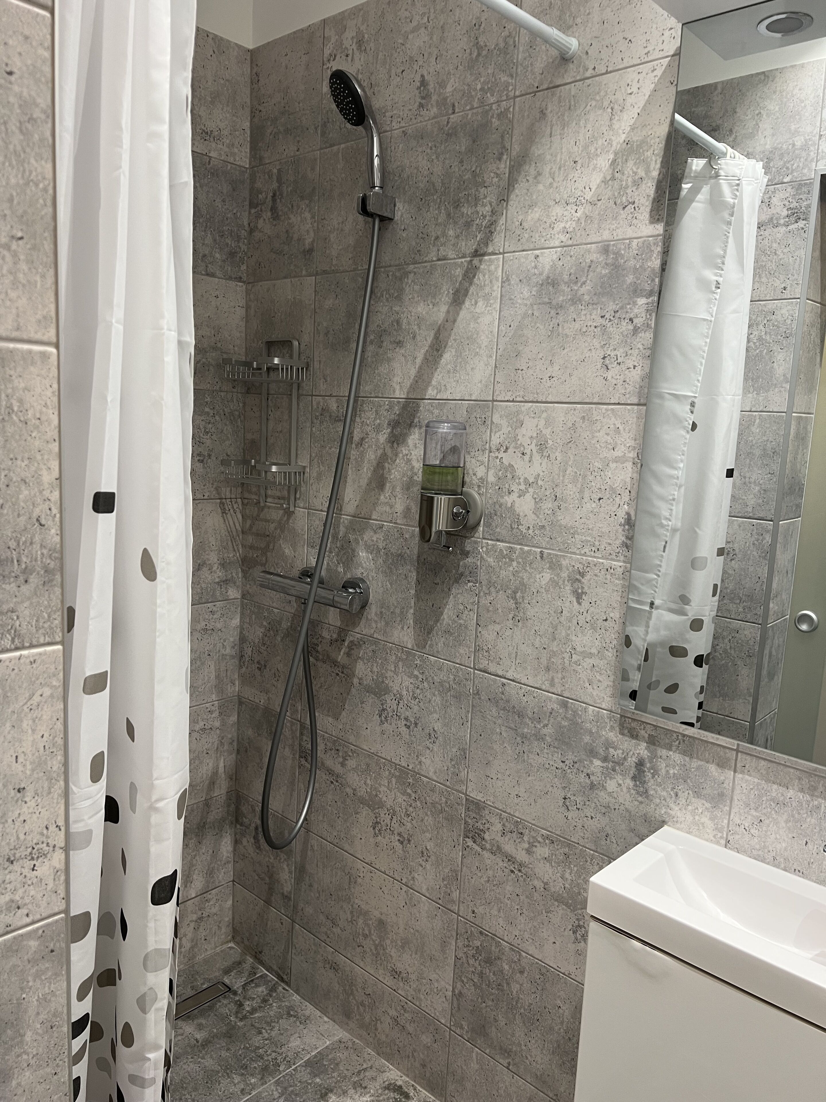 Ducha con cabezal de ducha de mano y panel de control en la pared.