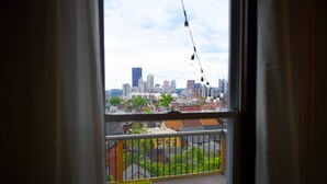 Un balcón con vistas a un horizonte urbano, una mesa de madera y una planta en maceta.