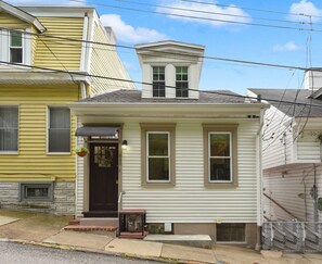 A two-story house with a front porch, a small garage, and a visible attic window.