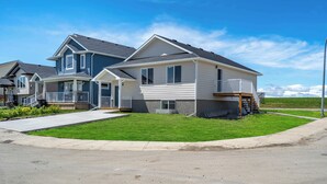 A two-story residential house with a front porch, a small deck, and a well-maintained lawn.
