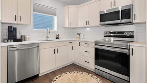 A modern kitchen with stainless steel appliances, light-colored cabinets, and a built-in oven.