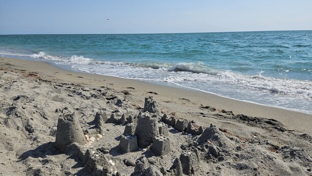 A sandy beach with waves and a clear sky.
