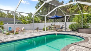 A covered outdoor swimming pool with a clear blue water feature, surrounded by a white metal frame and a blue umbrella.