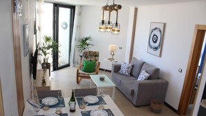 Een eethoek met een tafel voor vier personen, een bank en een stoel met een groen kussen.