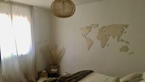 A bedroom with a bed, a world map on the wall, and a window with curtains. - Maison Dans Domaine Avec Piscine (Le Tholonet)