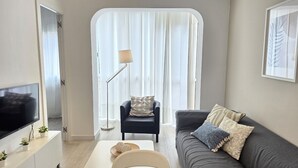 A modern living room with a flat-screen TV, a sofa, a chair, and a coffee table.
