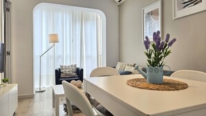 A modern dining area with a white table, chairs, and a decorative plant centerpiece.