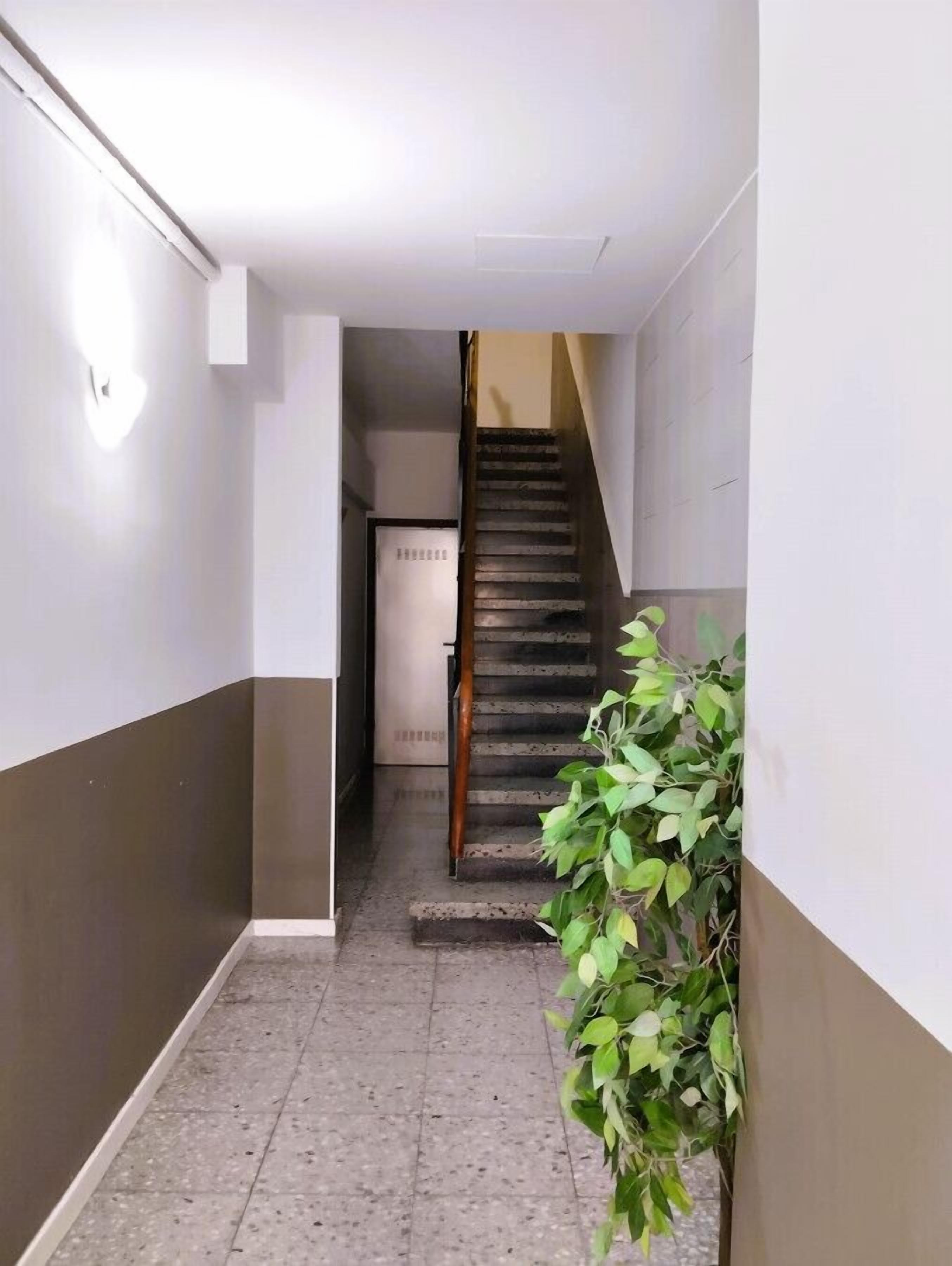 Ein schmaler Flur mit einer Treppe, die zu einer Zwischenebene führt.