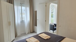 A bedroom with a bed, two towels, a chair, and a door leading to a balcony.