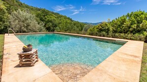 A rectangular swimming pool with clear water, surrounded by a wooden deck and a stone border. - Villa Olmo With Private Pool (Castel di Lucio)