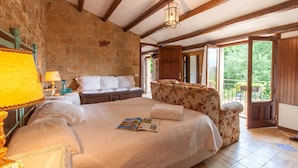 A bedroom with a large bed, a nightstand, a lamp, a chair, and a view of the outdoors. - Villa Olmo With Private Pool (Castel di Lucio)