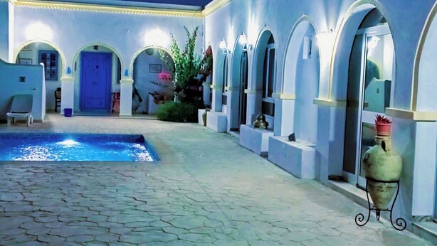 A courtyard with a swimming pool, arched doorways, and a tiled floor. - Dar Soulayma vacation home (Fatou houmet souk Djerba)