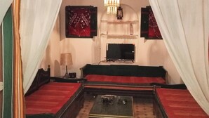 A room with a bed, a television, and a chandelier. - Dar Soulayma vacation home (Fatou houmet souk Djerba)