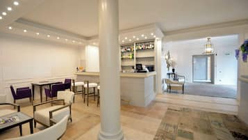 A hotel lobby with a bar area, seating arrangements, and a patterned carpet.
