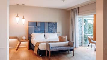 Een moderne slaapkamer met een groot bed, nachtkastjes, een bankje en uitzicht op groen door een glazen deur.