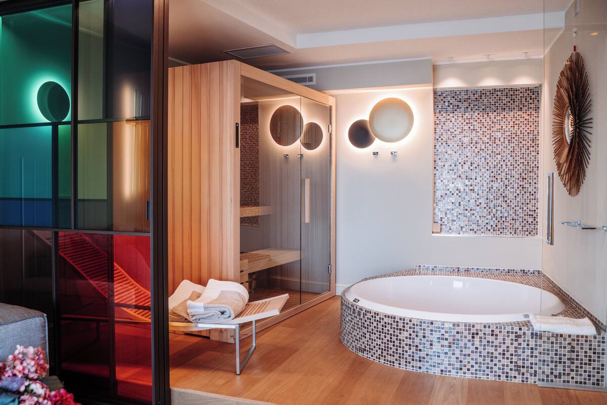 Une salle de bain moderne dotée d’une douche à parois de verre, d’une baignoire sur pieds et d’un meuble-lavabo en bois avec un miroir.