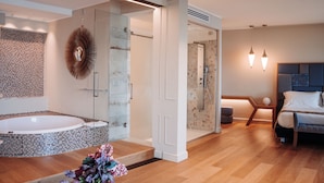Un baño moderno con ducha de vidrio, una bañera independiente y un espejo grande con diseño en forma de sol.