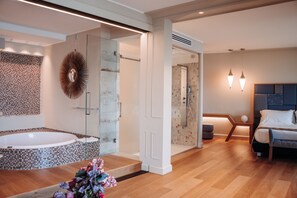 Un baño moderno con ducha de vidrio, una bañera independiente y un espejo grande con diseño en forma de sol.