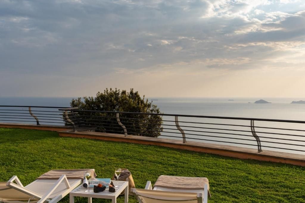 Una terrazza con poltrona relax e un tavolo, con vista su un corso d'acqua e isole in lontananza.