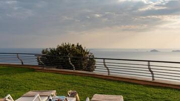 Una terrazza con poltrona relax e un tavolo, con vista su un corso d'acqua e isole in lontananza.