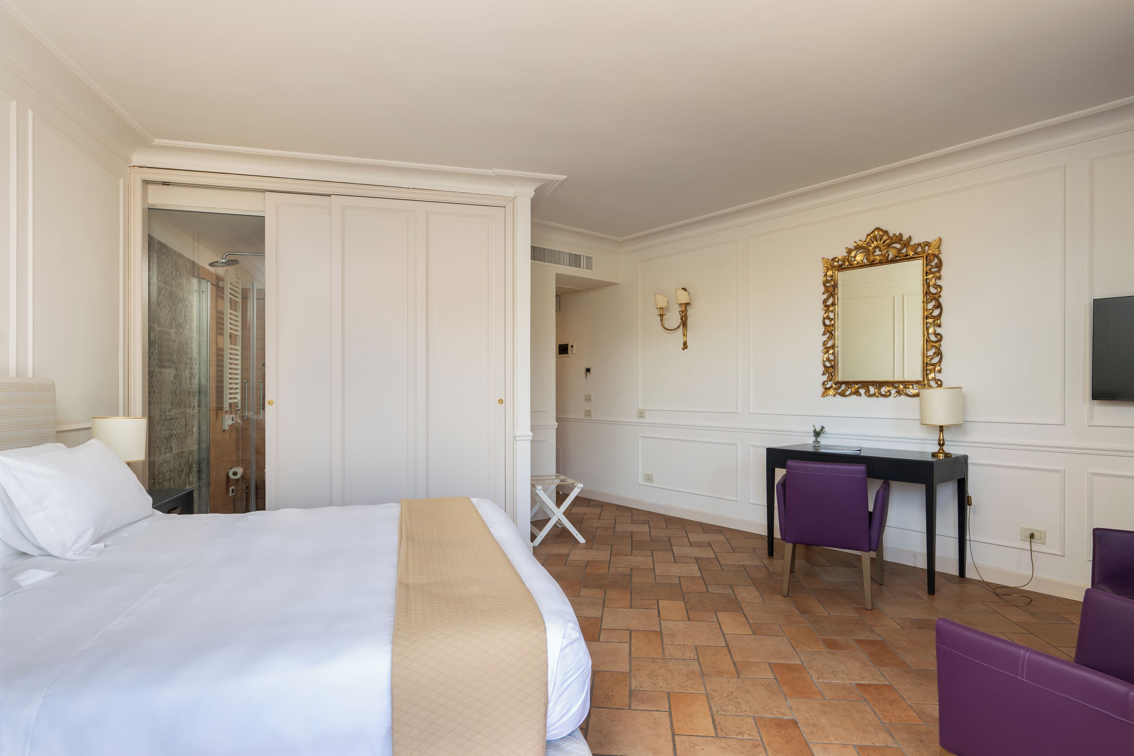 Une chambre d’hôtel équipée d’un lit, d’un bureau, d’une chaise, d’un miroir et d’un espace douche.
