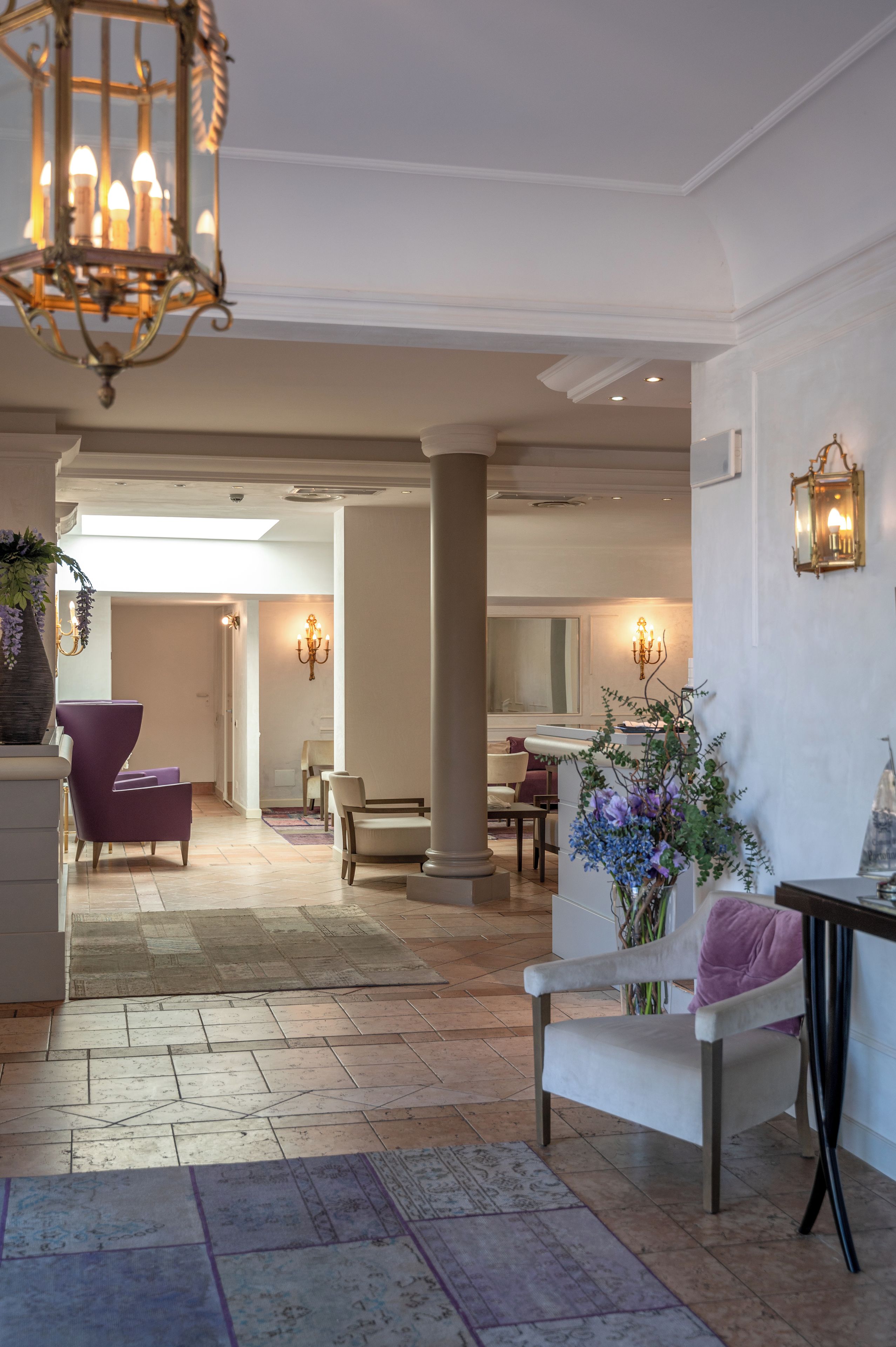 A spacious lobby with a high ceiling, a chandelier, and a seating area with chairs and a table.