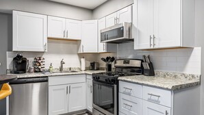 A modern kitchen with white cabinets, stainless steel appliances, and granite countertops.